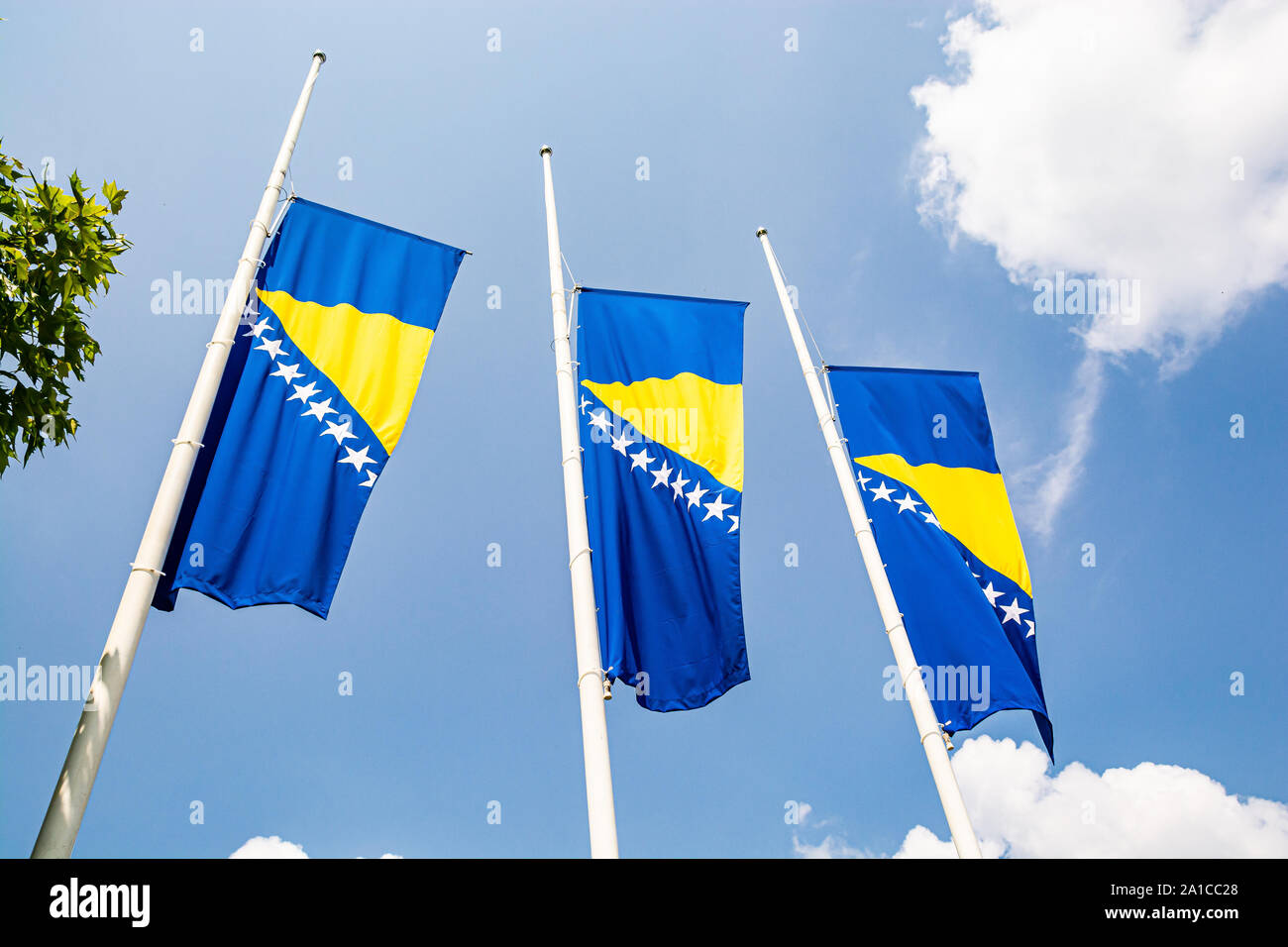 Drei bosnische Flaggen im Wind auf blauen Himmel mit Wolken Stockfoto
