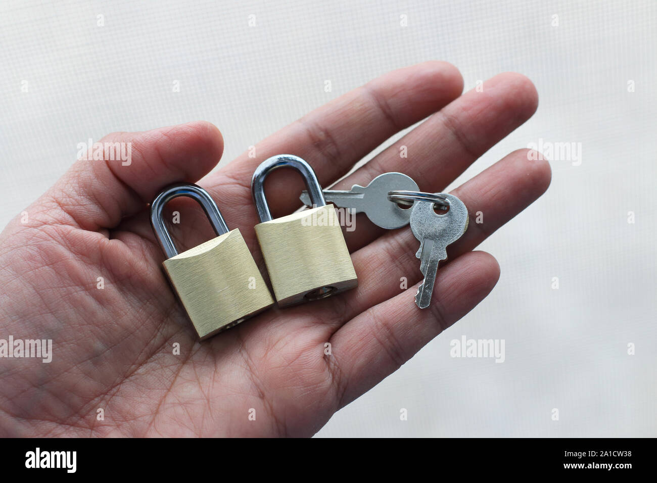 Hand mit Schlüssel und Schlösser vor weißem Hintergrund Stockfoto