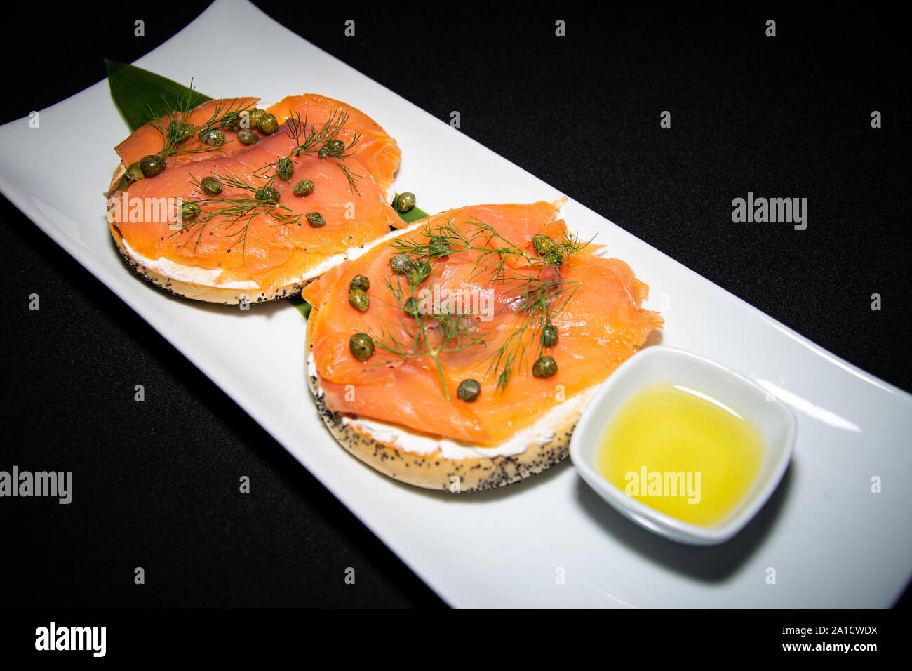 Eine gesunde geräucherten Lachs und Frischkäse Bagel serviert mit einer Portion Knoblauch Olivenöl Stockfoto