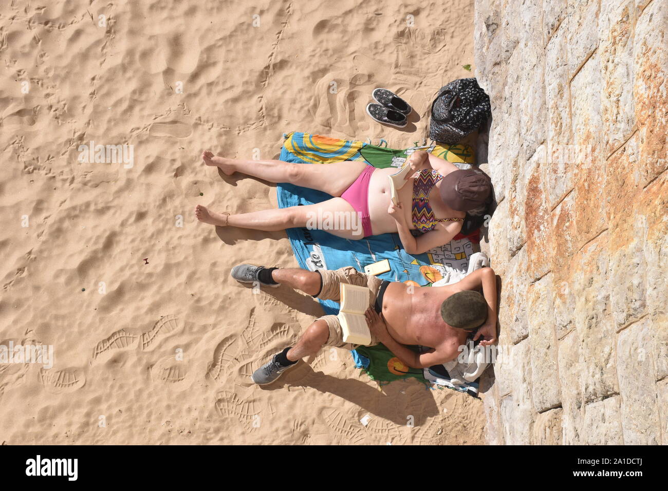 Direkt oberhalb der Schuß von Paar sitzt auf einem Sandstrand Stockfoto
