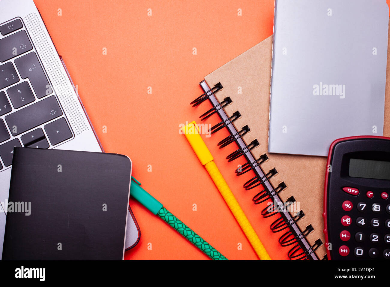 Ansicht von oben Foto flach mockup Foto von Arbeitsbereich mit Laptop, Taschenrechner, Stifte und Notebook auf orange Pastell Hintergrund. Stockfoto