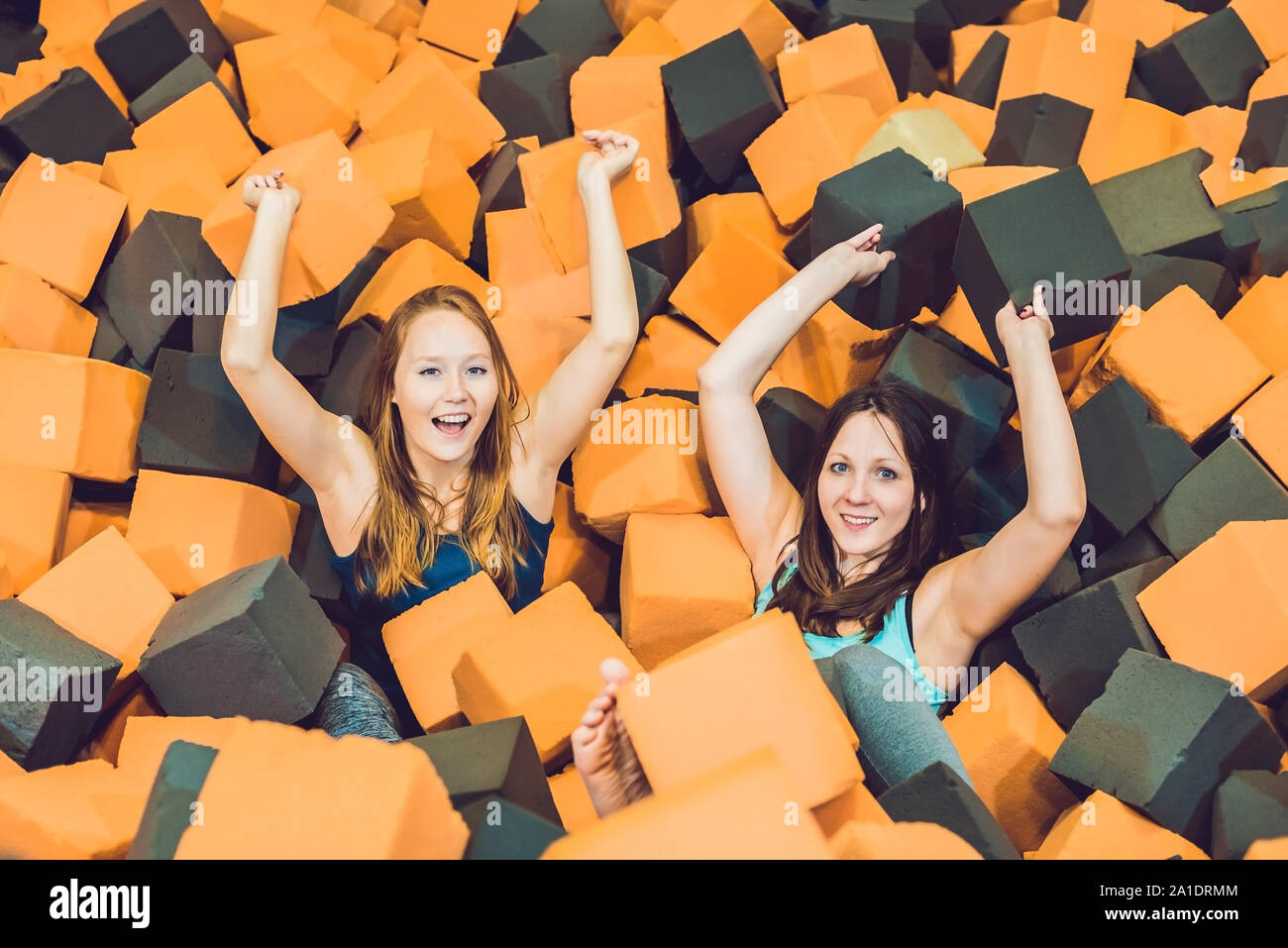 Zwei junge Frauen, die Spaß haben mit weichen Blocks, an Indoor Spielplatz in der Schaumgummi Grube im Trampolin center. Stockfoto