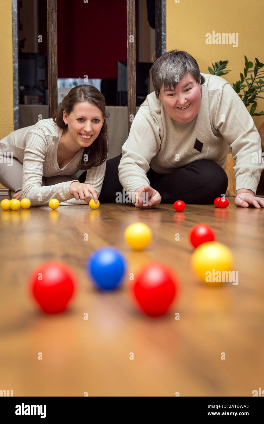 Betreuer und geistig behinderte Frau spielen mit Bällen, alternative Lernen Stockfoto