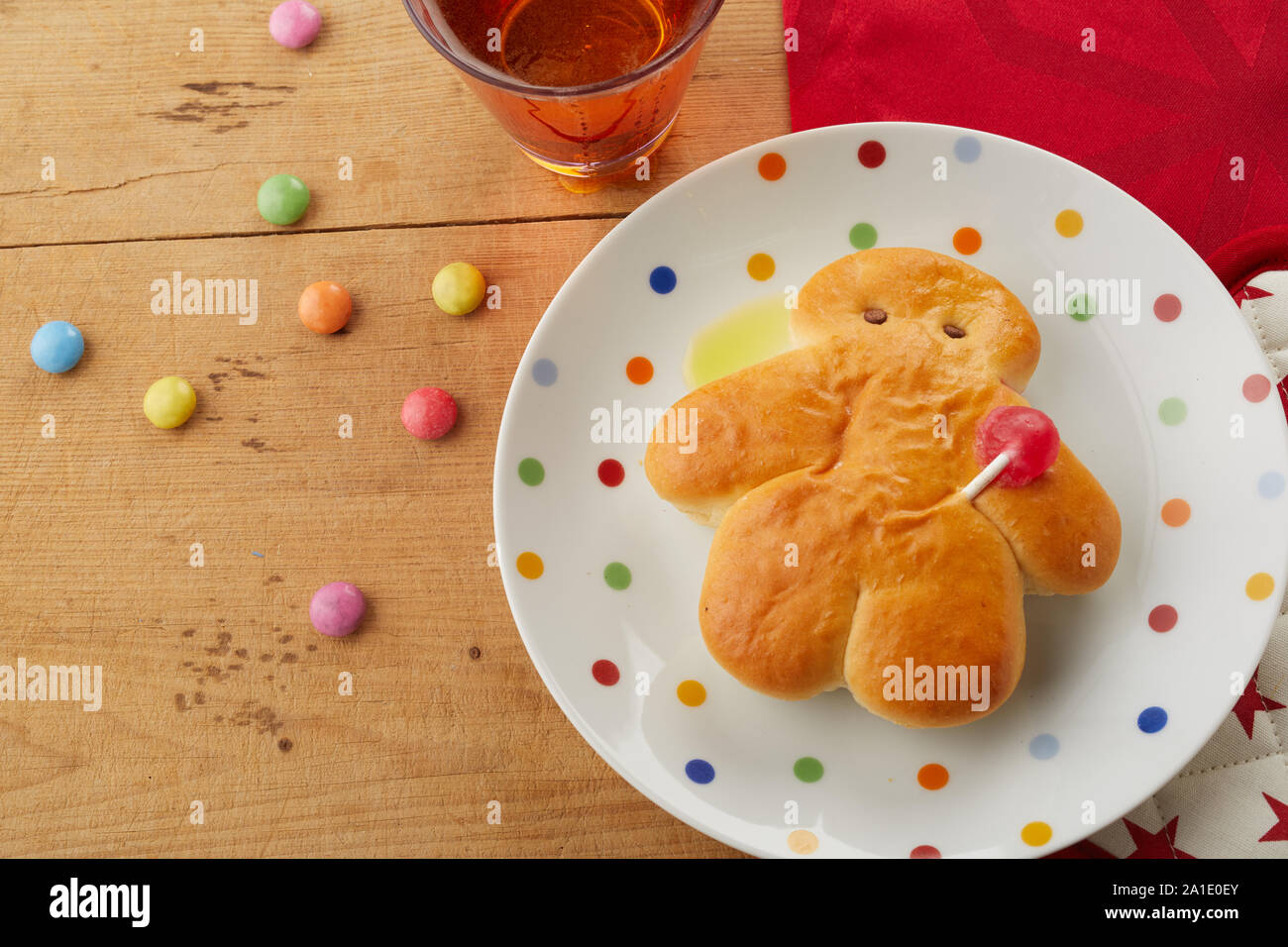 Mini Stuten Brot Mann auf einer Polka Dot Platte mit bunten Süßigkeiten und ein Glas trinken von oben auf einen festlichen Tisch gesehen für den Hl. Nikolaus feiern Stockfoto