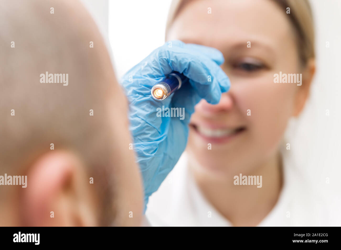 Weibliche professionell Specialist ist das Auge von einem männlichen Patienten mit einem elektrischen Licht prüfen Stockfoto