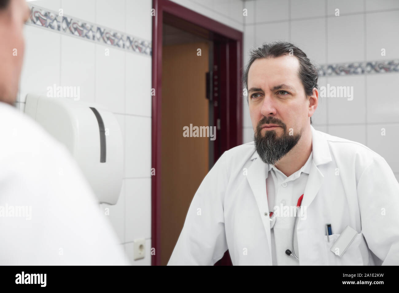 Betonte auf der Suche Arzt vor einem Spiegel beobachtet sich selbst Stockfoto