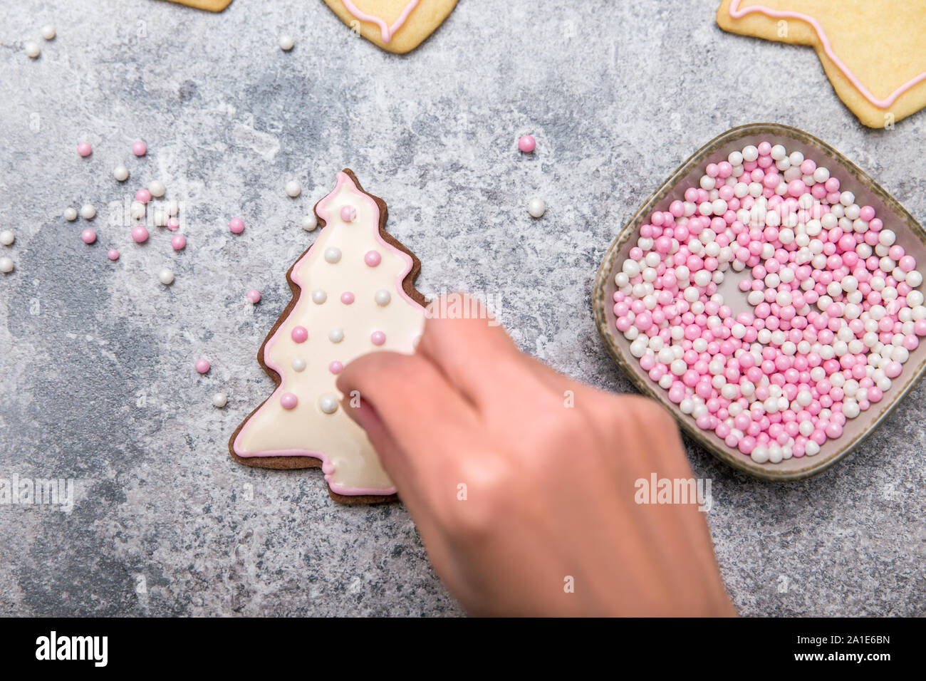 Weihnachtsplätzchen Dekoration mit Royal icing, Zuckerguss und rosa Zucker Perlen, Arbeitsschritt Stockfoto