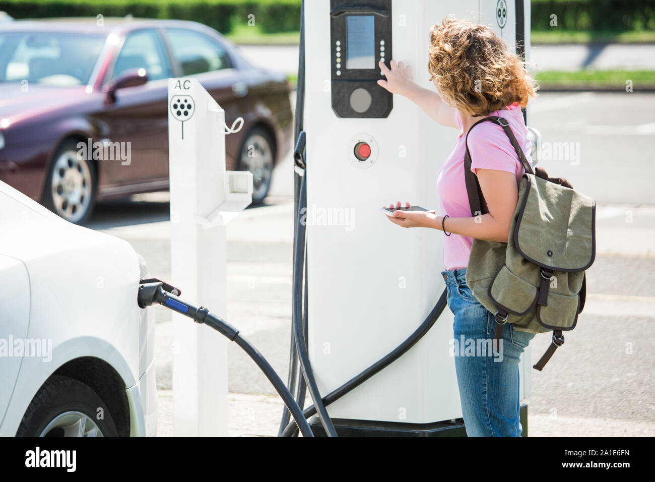 Eine Frau steuert eine Ladestation für Elektroautos Stockfoto