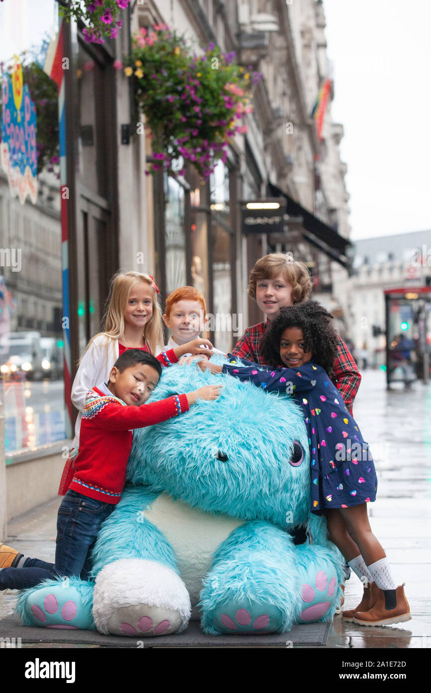 Einige glückliche Kinder erhielten eine Reise nach Hamleys für den Start Ihrer 10 Spielzeug für Weihnachten auf der Regent Street. Hier die Kinder kuscheln um einen riesigen Scruf-a-Luv Spielzeug. Stockfoto