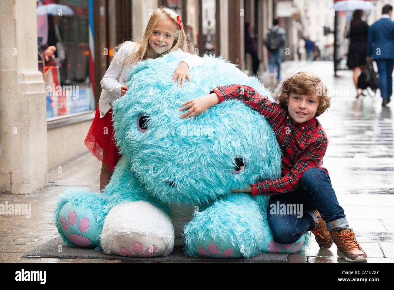 Einige glückliche Kinder erhielten eine Reise nach Hamleys für den Start Ihrer 10 Spielzeug für Weihnachten auf der Regent Street. Hier die Kinder kuscheln um einen riesigen Scruf-a-Luv Spielzeug. Stockfoto