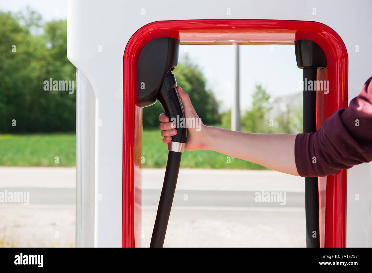 Ein Mann steht hält einen Stecker der Kompressormotoren für ein Elektrofahrzeug Stockfoto Ein Mann steht hält einen Stecker der Kompressormotoren für ein Elektrofahrzeug Stockfoto