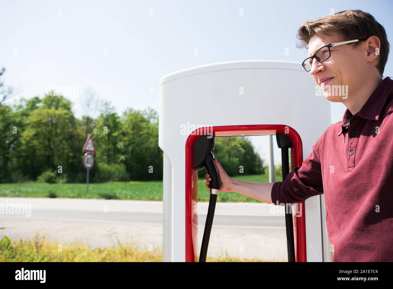 Ein Mann steht hält einen Stecker der Kompressormotoren für ein Elektrofahrzeug Stockfoto Ein Mann steht hält einen Stecker der Kompressormotoren für ein Elektrofahrzeug Stockfoto