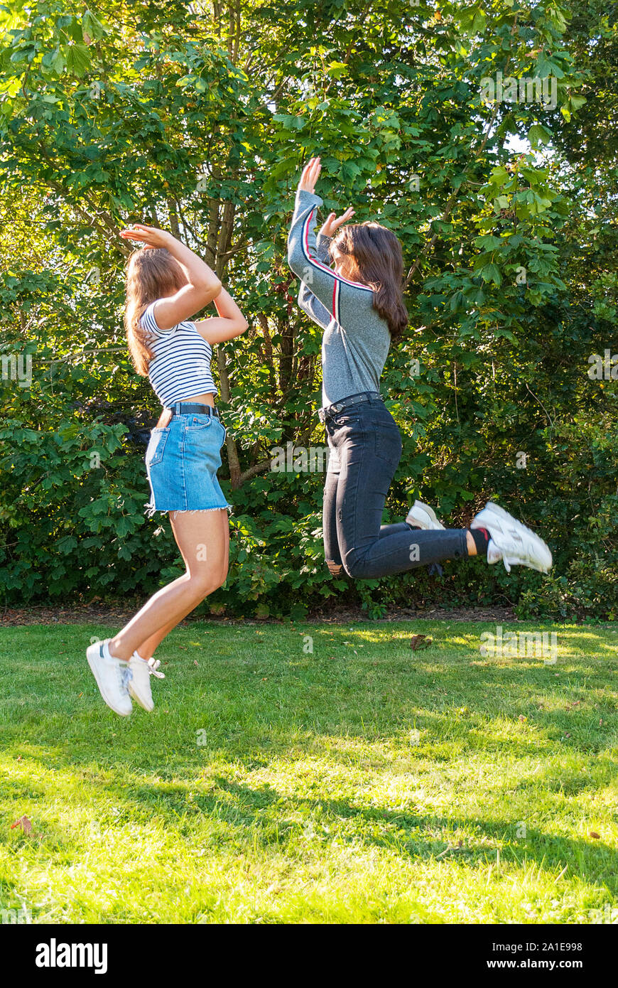 Zwei jugendliche Mädchen springen in einem Park im Sommer. Spaß haben im Urlaub. Gerne Freunde Zeit miteinander zu verbringen. Freundschaft. Stockfoto