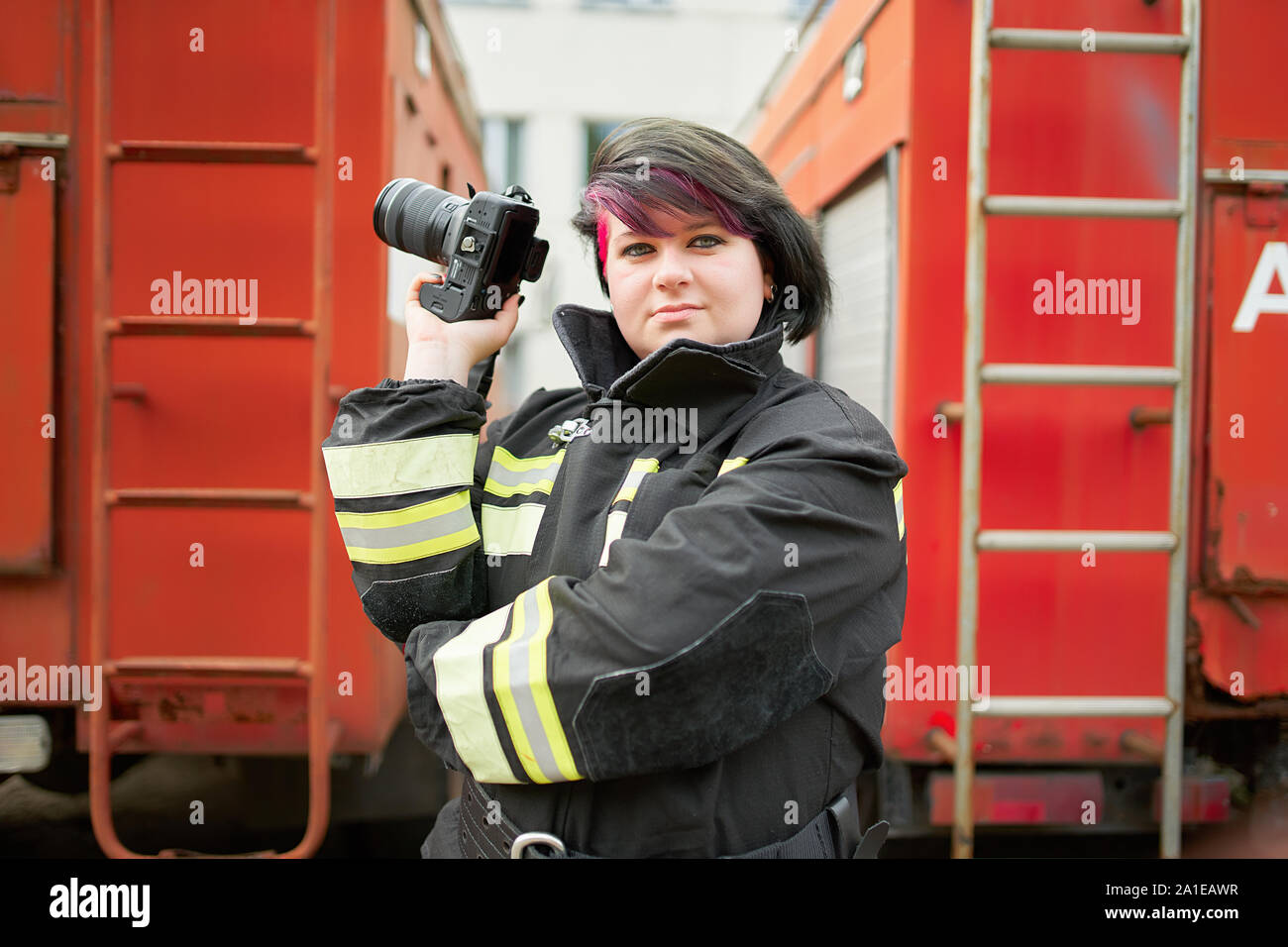 Bild von brunette Feuerwehrmann mit Kamera zur Hand neben Feuerwehr Auto auf der Straße Stockfoto