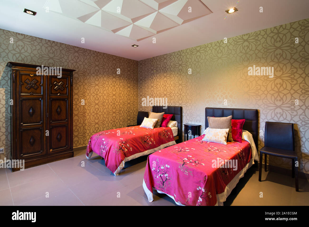 Modernes Haus Zimmer, mit Tapeten und zwei Einzelbetten mit fuchsia Bettdecken. Dekorative Decke. Stockfoto