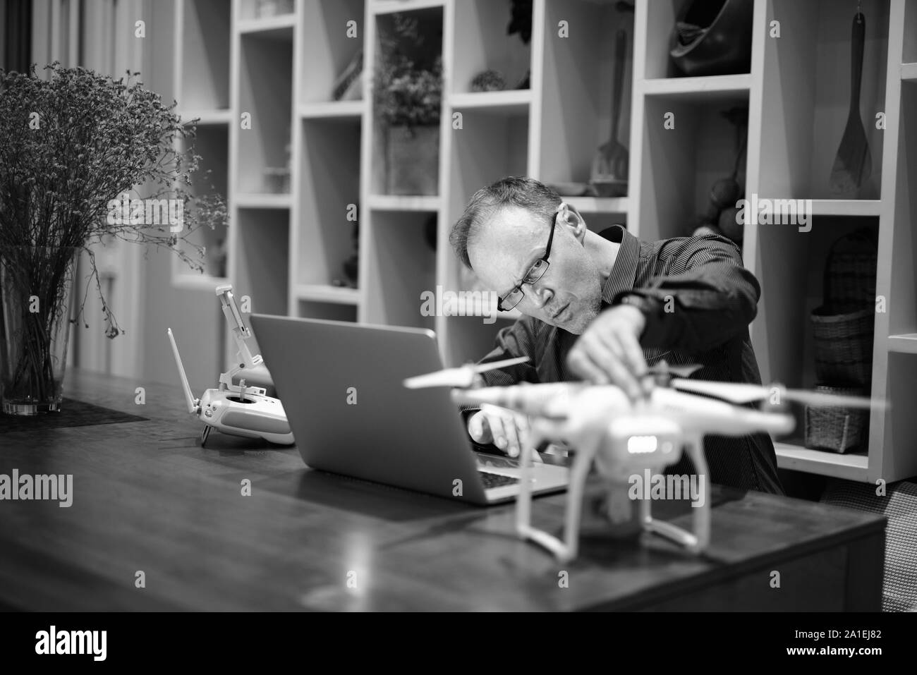 Reifer Mann mit Kamera Drohne mit Laptop Stockfoto