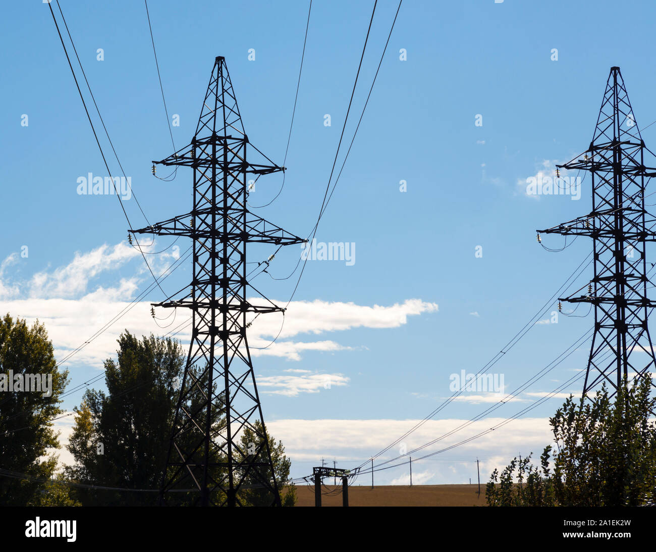 Zwei Masten der Hochspannungsleitung mit Glas Isolatoren und Leitungen vor einem blauen Himmel mit weißen Wolken Stockfoto