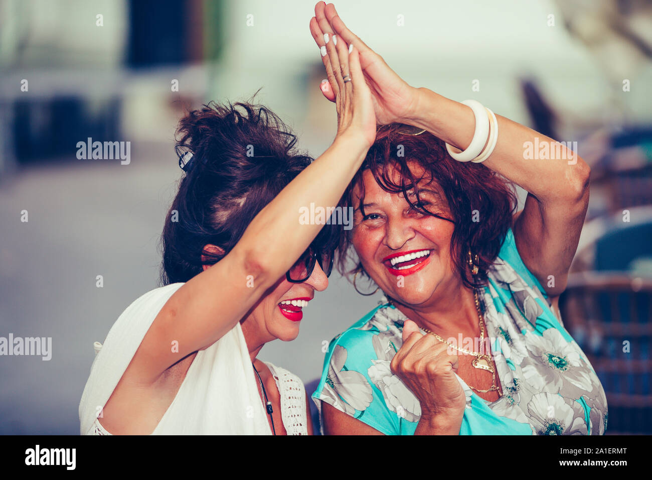 Gerne ältere weibliche Freunde geben High Five, Erfolg feiern, während Sie einander sitzen, die in der Tabelle in einem Café im Freien. Stockfoto