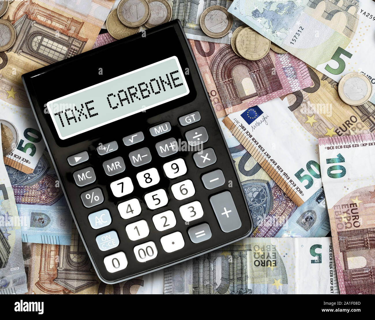 Close-up Text STEUER CARBONE, Französisch für CO2-Steuer, auf Anzeige von Taschenrechner gegen Euro Scheine auf Tabelle Stockfoto