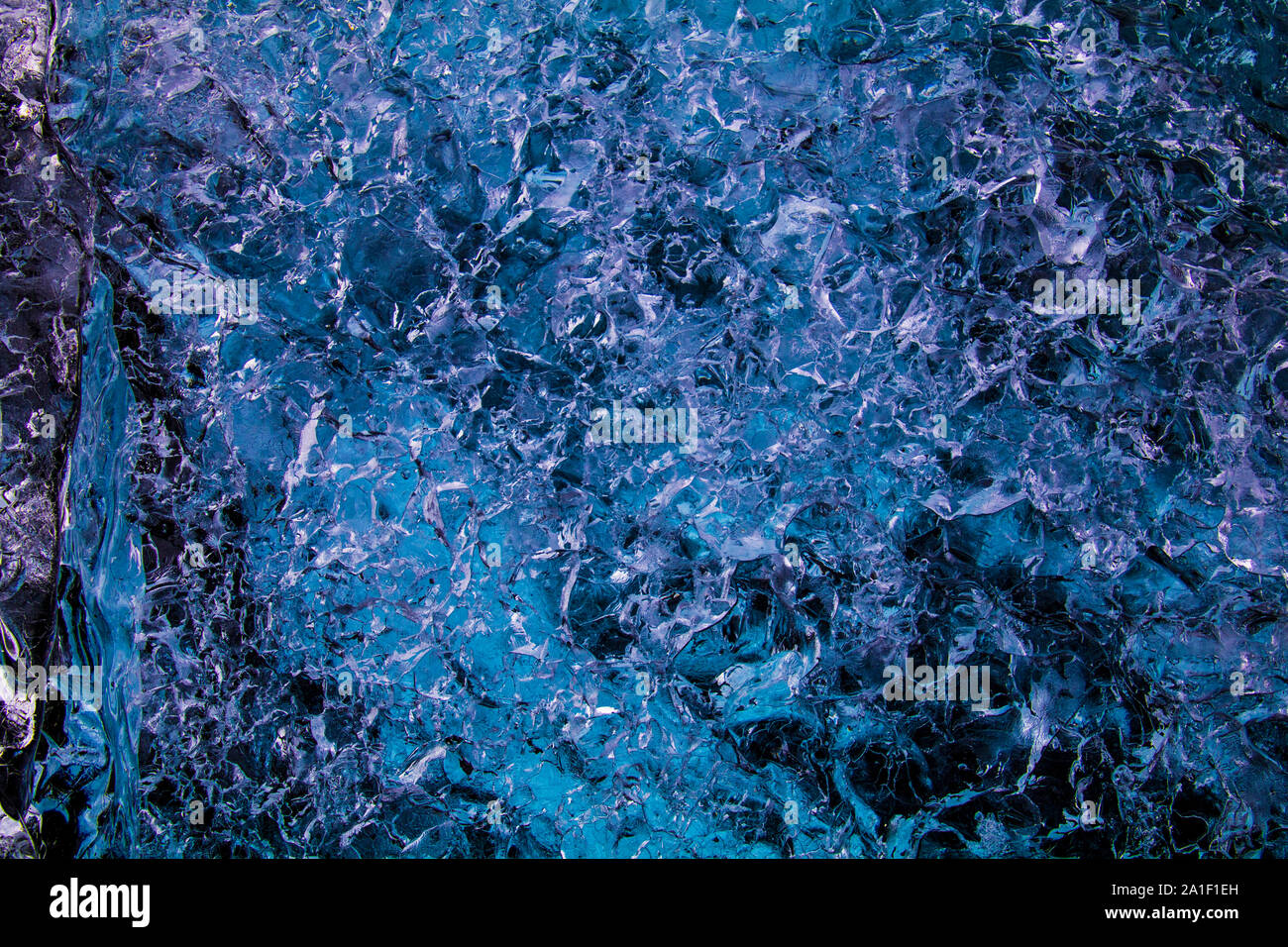 Eisscholle auf schwarzem Sand Strand mit Meer und bewölkter Himmel im Hintergrund. In der Lagune Jökulsarlon im Süden von Island fotografiert. Stockfoto