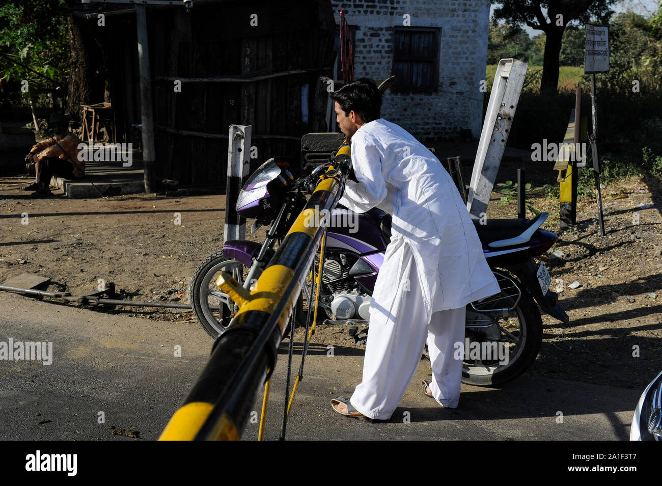 Indien, Madhya Pradesh, Nimad region, Khargone, Motorrad fahrer verletzen Verkehrsregeln während ein Bahnübergang Kreuzung mit geschlossenen Schranken Stockfoto