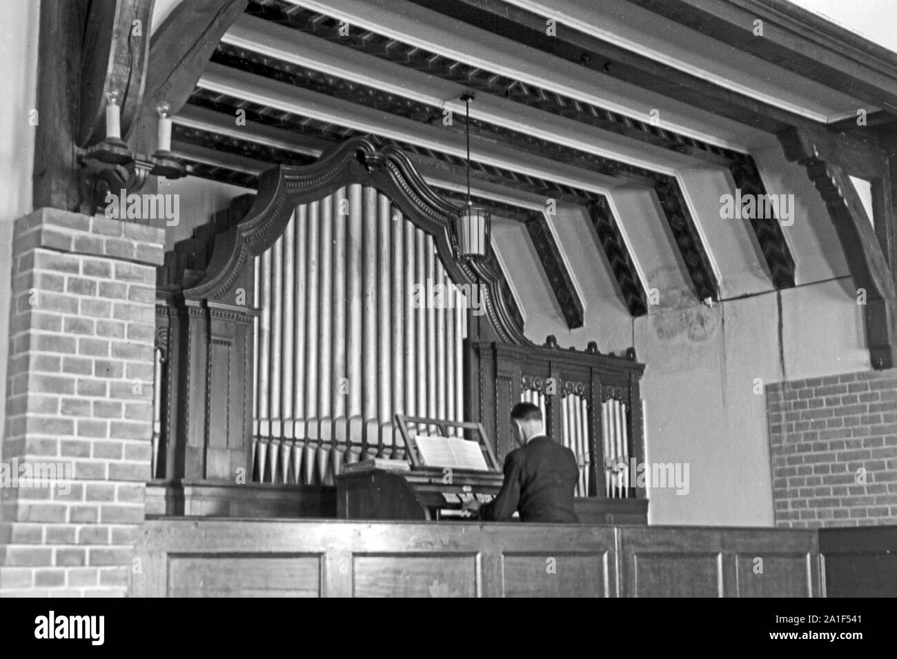 Der Organist spielt die Orgel im Zusatzger&aumlte einer Kapelle des Kinder-und Pflegeheimes in Frankfurt/Oder, Deutschland 1948. Die Orgel in der Kapelle der Kinder und Pflegeeltern von Nonnen und Schwestern in Frankfurt/Oder, Deutschland 1948 geführt. Stockfoto