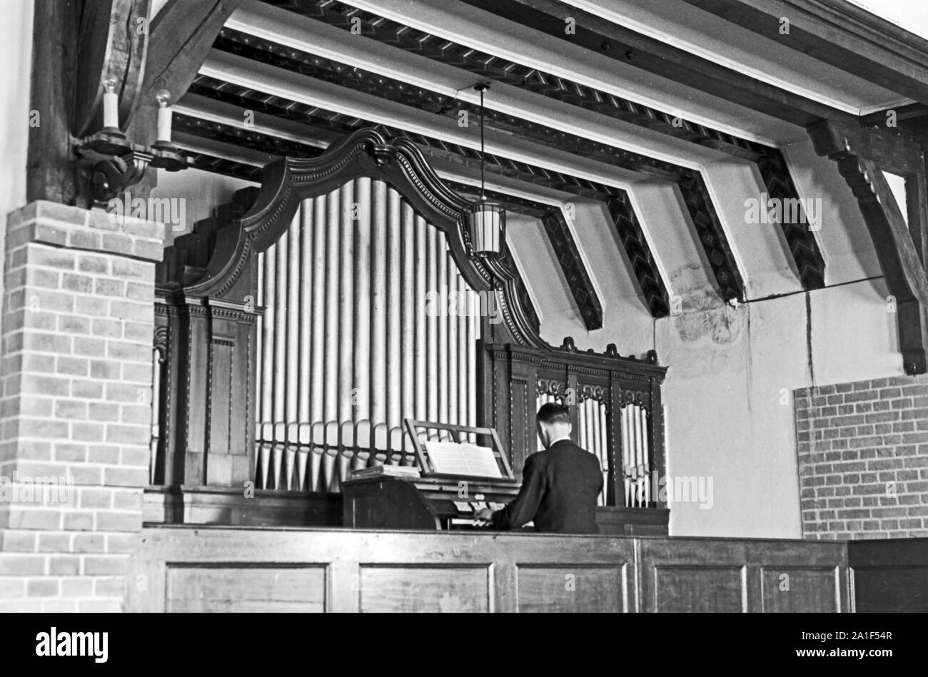 Der Organist spielt die Orgel im Zusatzger&aumlte einer Kapelle des Kinder-und Pflegeheimes in Frankfurt/Oder, Deutschland 1948. Die Orgel in der Kapelle der Kinder und Pflegeeltern von Nonnen und Schwestern in Frankfurt/Oder, Deutschland 1948 geführt. Stockfoto