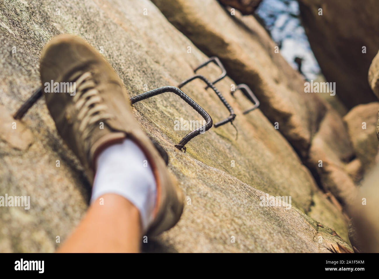 Beine von Reisenden sittingon auf einem Felsen mit Eisen Treppen in Reisen. Freiheit Konzept. Stockfoto