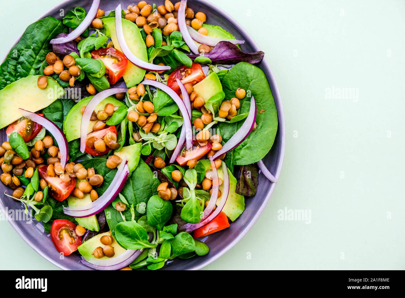 Gesunde vegetarische oder vegane Avocado- und Linsensalat, mit roten Zwiebeln, grüner Salat Blätter andcopy Raum, Cherry Tomaten Stockfoto