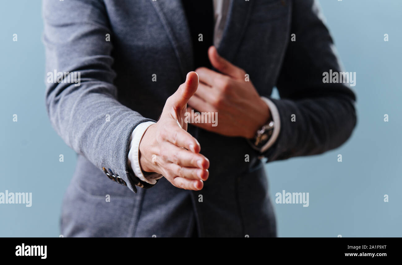 Geschäftsmann im Anzug zur Verlängerung der Hand, bereit für Handshake über blauer Hintergrund Stockfoto