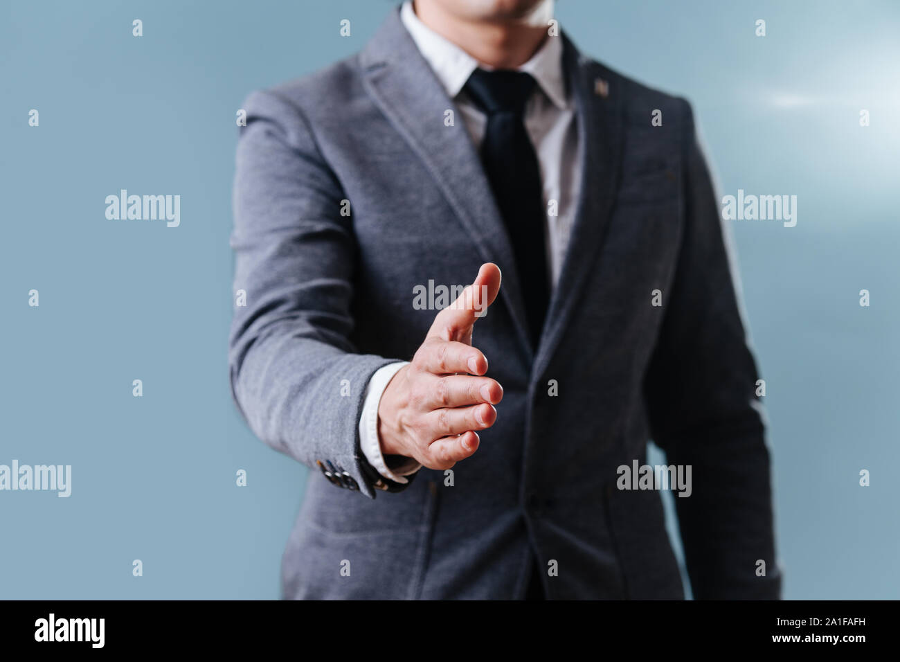 Geschäftsmann im Anzug zur Verlängerung der Hand, bereit für Handshake über blauer Hintergrund Stockfoto