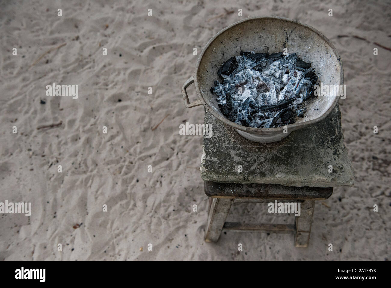 Alte pan mit verbrannten Kohle über Holz Werkbank auf sandigen Boden gefüllt Stockfoto