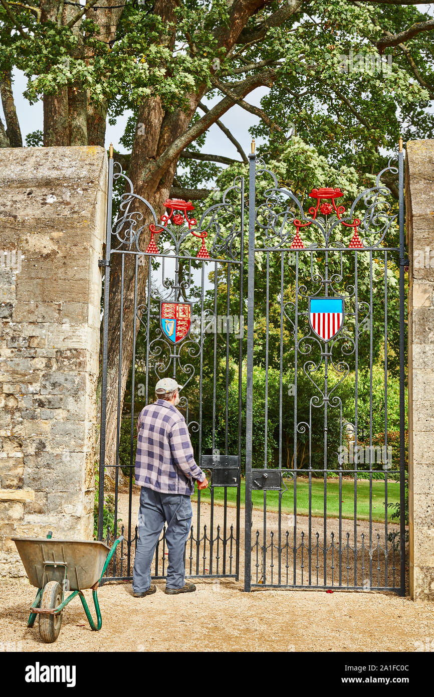 Ein Gärtner mit seiner Schubkarre am Christ Church College an der Universität Oxford, England, schließt das eiserne Tor, als er den Garten des Master verlässt. Stockfoto
