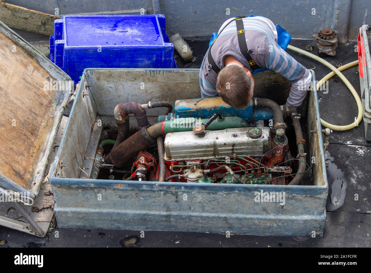 Mann bei der Arbeit auf seinem Boot, Motor Stockfoto