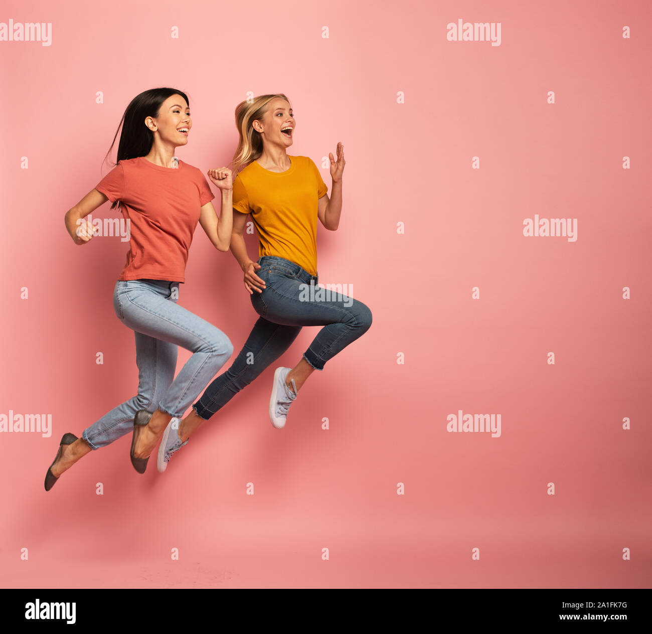 Zwei Mädchen laufen schnell. Konzept der Energie und Vitalität. Rosa Hintergrund Stockfoto