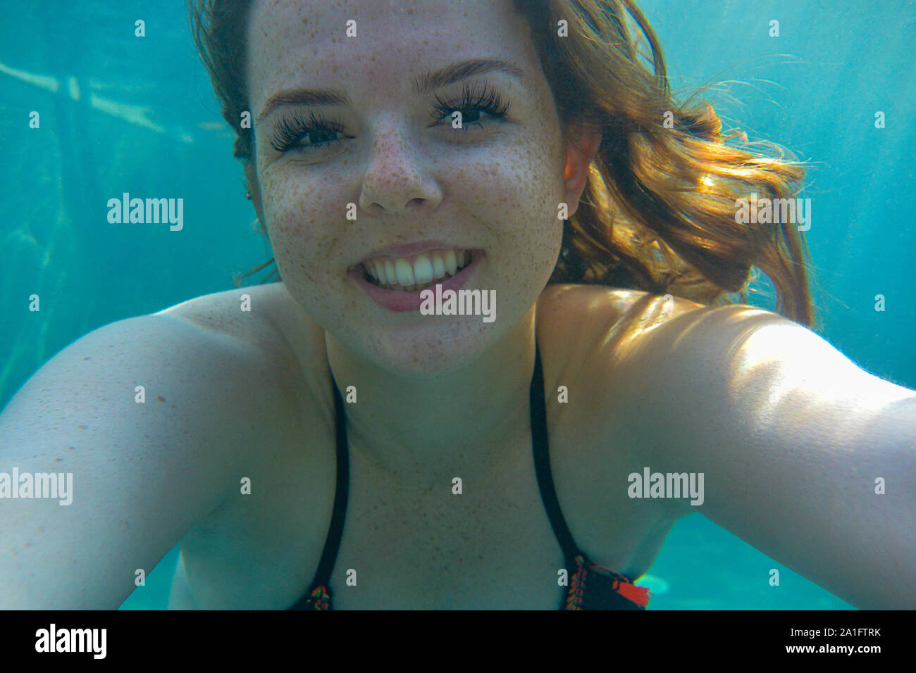 Schöne junge Frau nimmt eine selfie Unterwasser in einem Schwimmbad. Weibliche Spaß im Sommer. Stockfoto