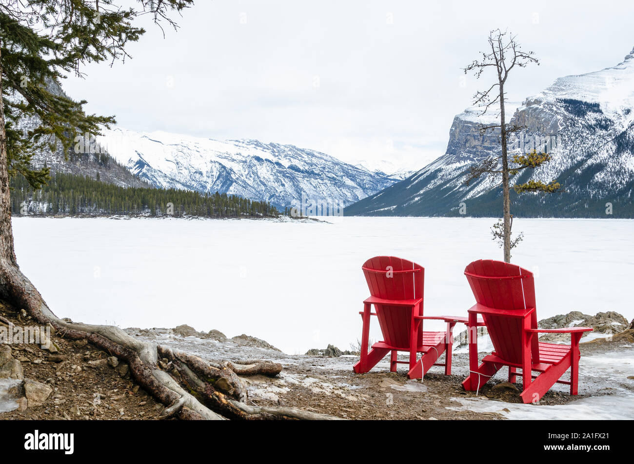 Leeren roten Stühlen mit Blick auf einen wunderschönen gefrorenen Bergsee an einem trüben Wintertag. Banff National Park, AB, Kanada. Stockfoto