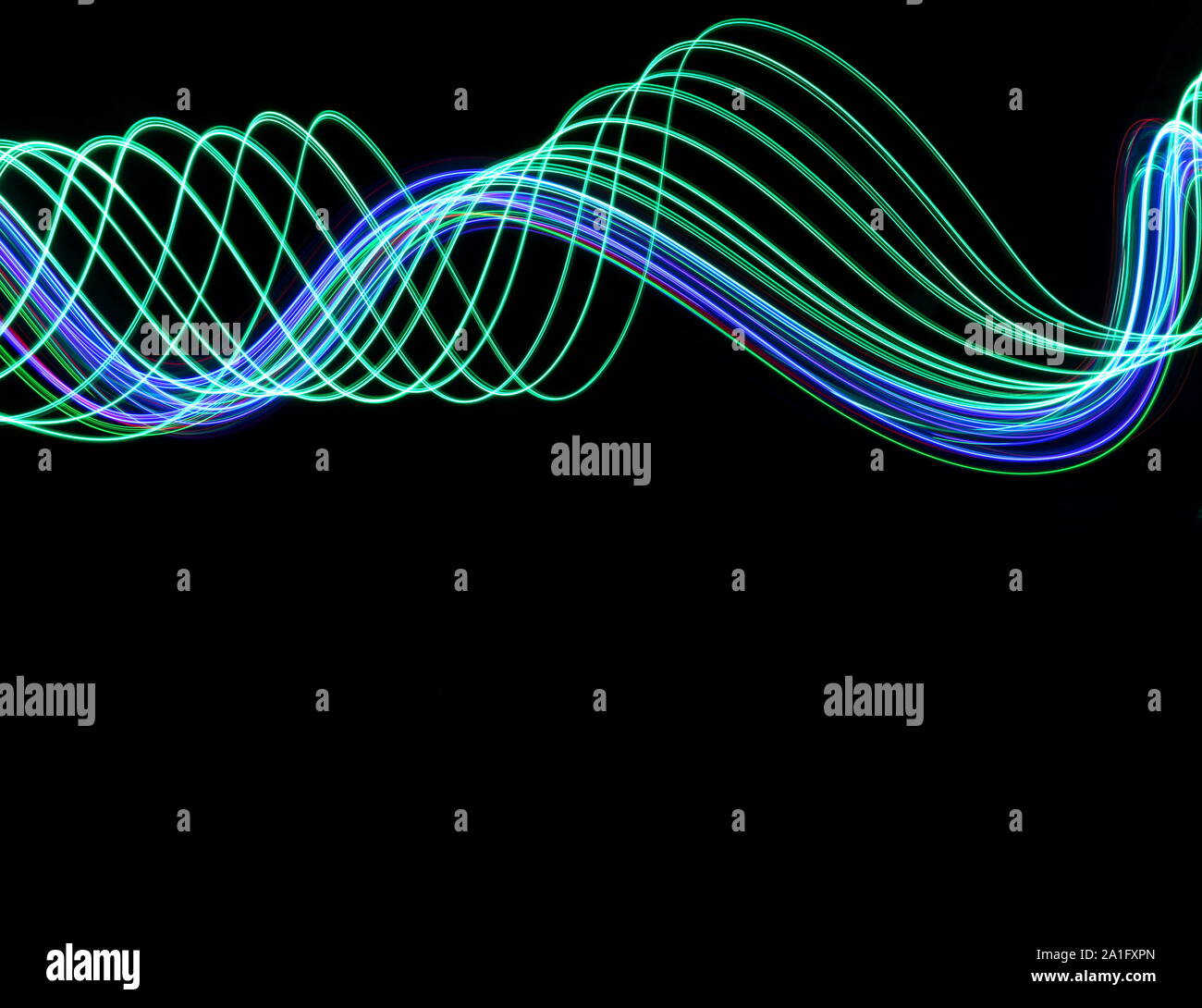 Lange Belichtung Foto von Neon Grün und Blau in einer abstrakten Wirbeln, parallele Linien Muster vor einem schwarzen Hintergrund. Licht Malerei Hg Stockfoto