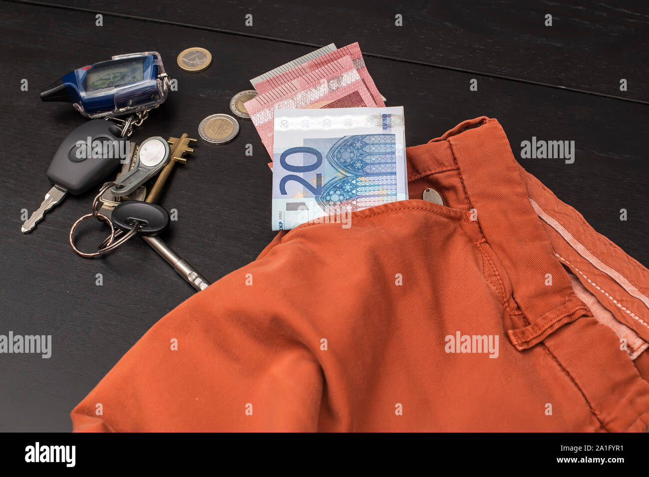 Euro Papiergeld und Münzen fielen aus der Tasche auf einem Schwarzen Tisch, auf dem eine Reihe von Haus und Auto Stockfoto