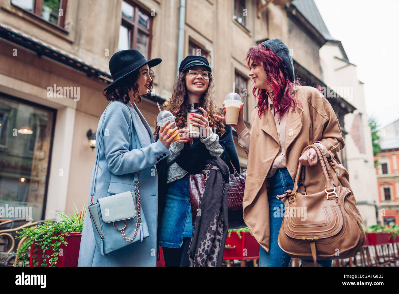 Drei weibliche Freunde Drinks im Freien. Frauen klirren Kaffee, Orangensaft und Kaffee Tassen Stockfoto
