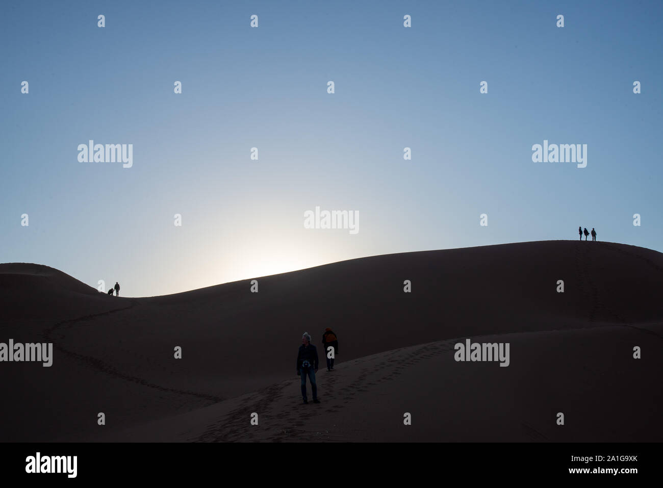 Menschen auf Sanddünen bei Sonnenuntergang in der Wüste von Marokko Stockfoto