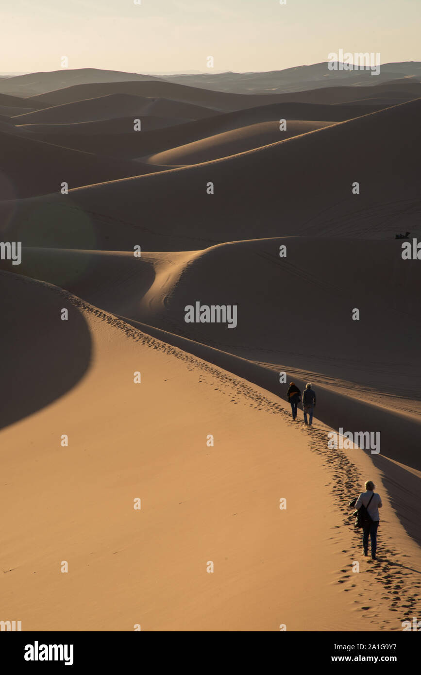 Menschen auf Sanddünen bei Sonnenuntergang in der Wüste von Marokko Stockfoto