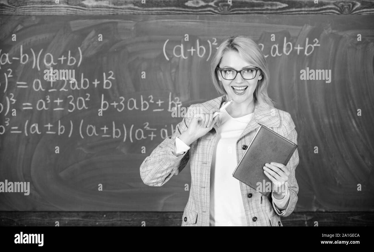 Lehre Komplex vielfältige Tätigkeit. Lehrer intelligente Frau mit Buch erklären Thema in der Nähe der Tafel. Was macht die großen Lehrer. Schule Lehrer erklären, Dinge gut und interessant machen. Stockfoto