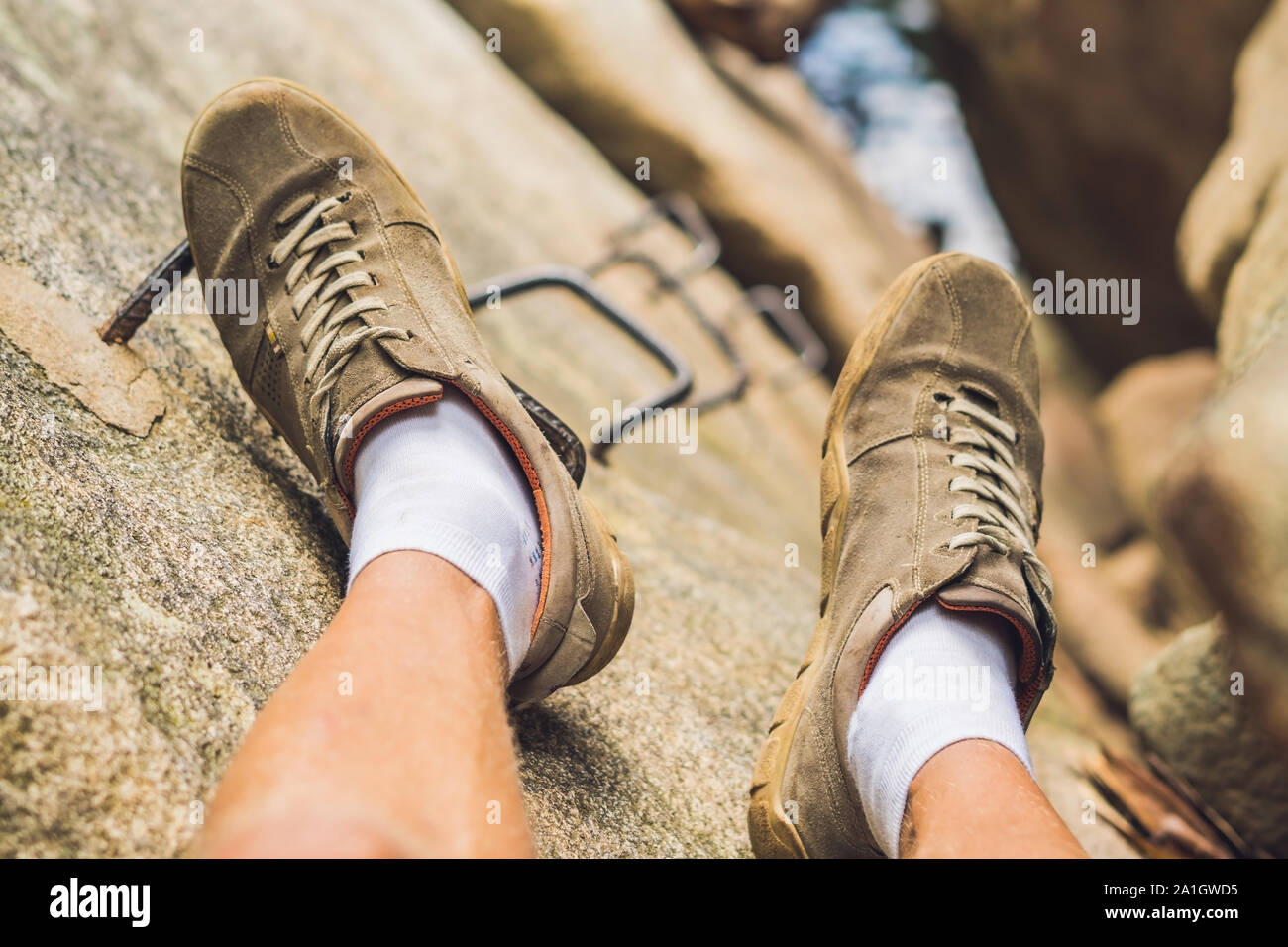 Beine von Reisenden sittingon auf einem Felsen mit Eisen Treppen in Reisen. Freiheit Konzept. Stockfoto