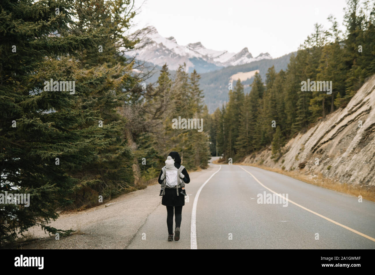 Frau Baby auf dem Rücken entlang eine Landstraße in den Bergen Stockfoto