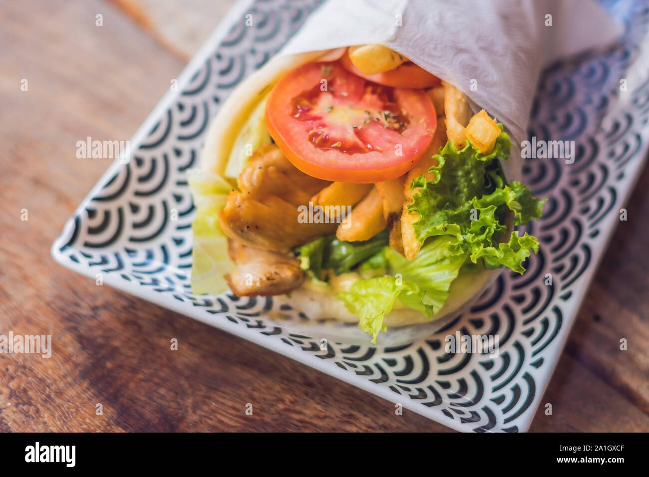 Griechische Gyros in pita Brot auf einem hölzernen Hintergrund gewickelt. Griechische küche Konzept. Stockfoto