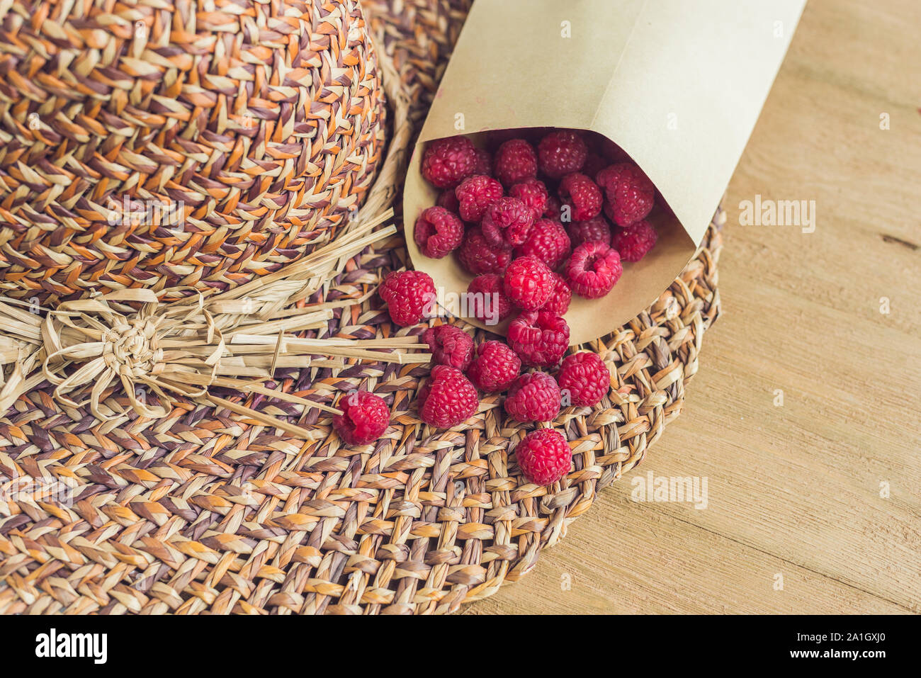 Sommer Urlaub, Ferien, Entspannung Konzept. Himbeeren, Stroh Hut, auf Holz- Hintergrund. Freier Text kopieren. Sommer vibes Konzept Stockfoto