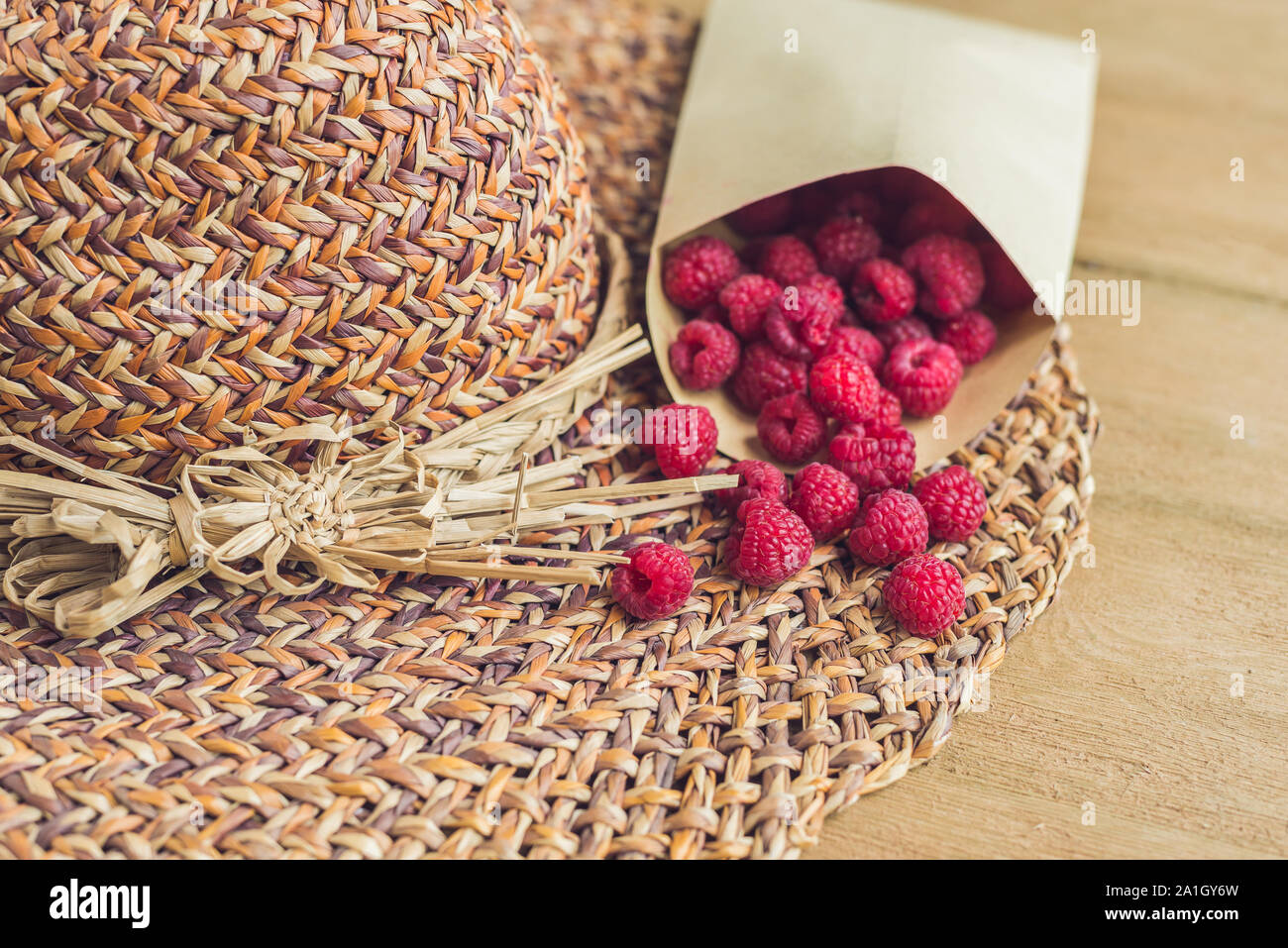 Sommer Urlaub, Ferien, Entspannung Konzept. Himbeeren, Stroh Hut, auf Holz- Hintergrund. Freier Text kopieren. Sommer vibes Konzept Stockfoto