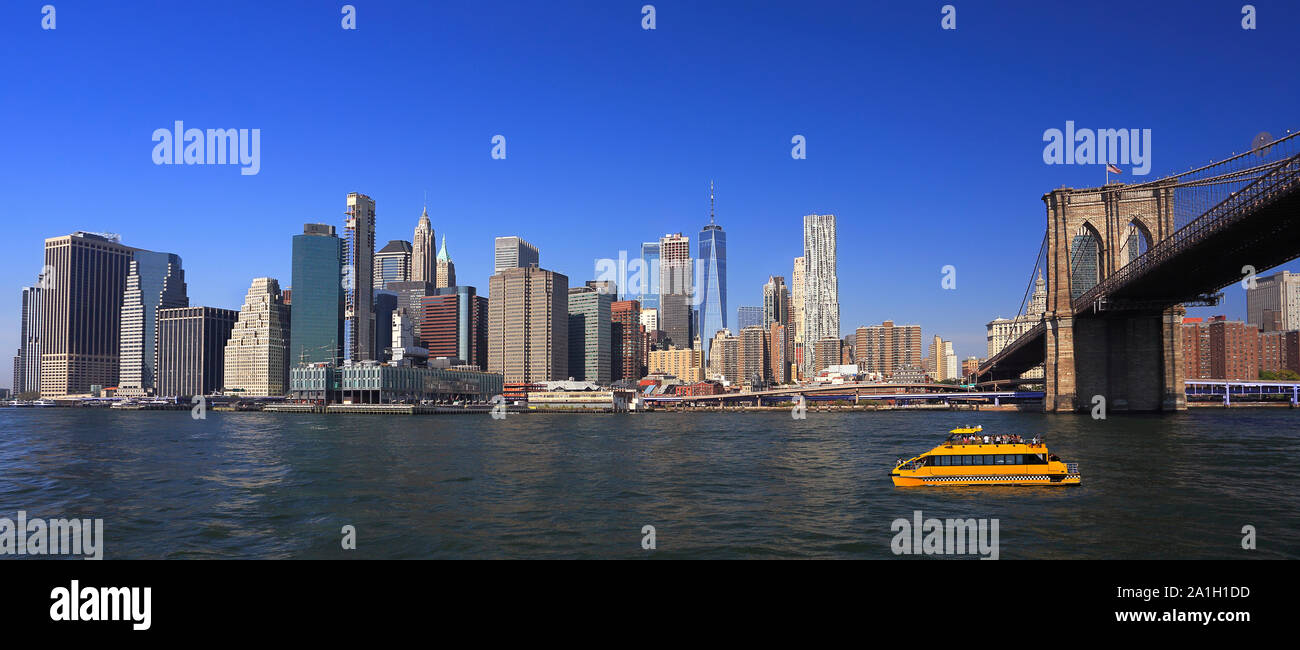 Lower Manhattan Skyline, Ost Fluss und Brooklyn Bridge mit einem gelben Wasser Taxi Boot im Vordergrund, New York City Stockfoto