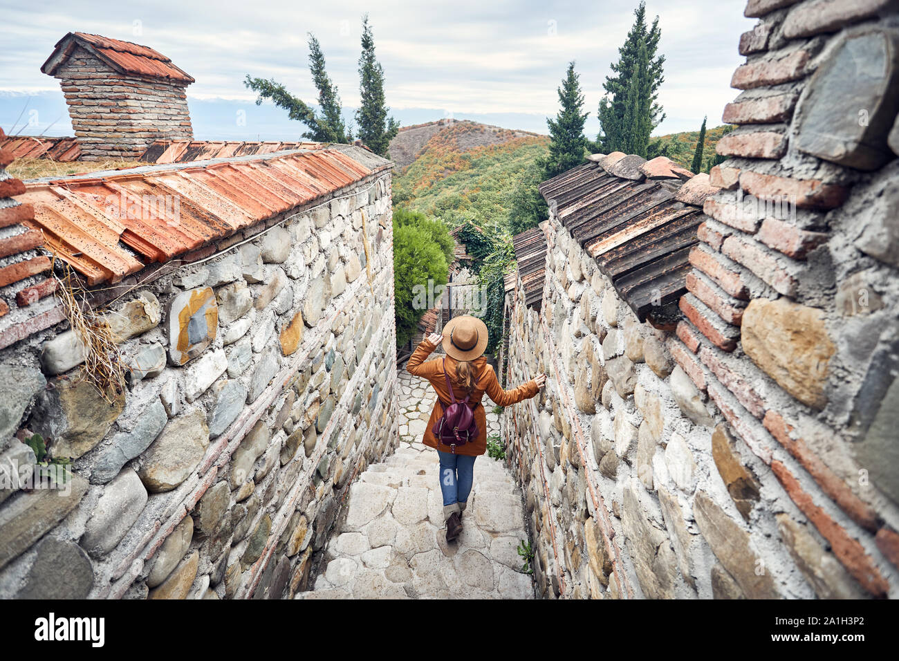 Touristische Frau in Hut gehen hinunter an der steinernen Treppe im alten Bodbe Monastery in Signagi, Georgien Stockfoto